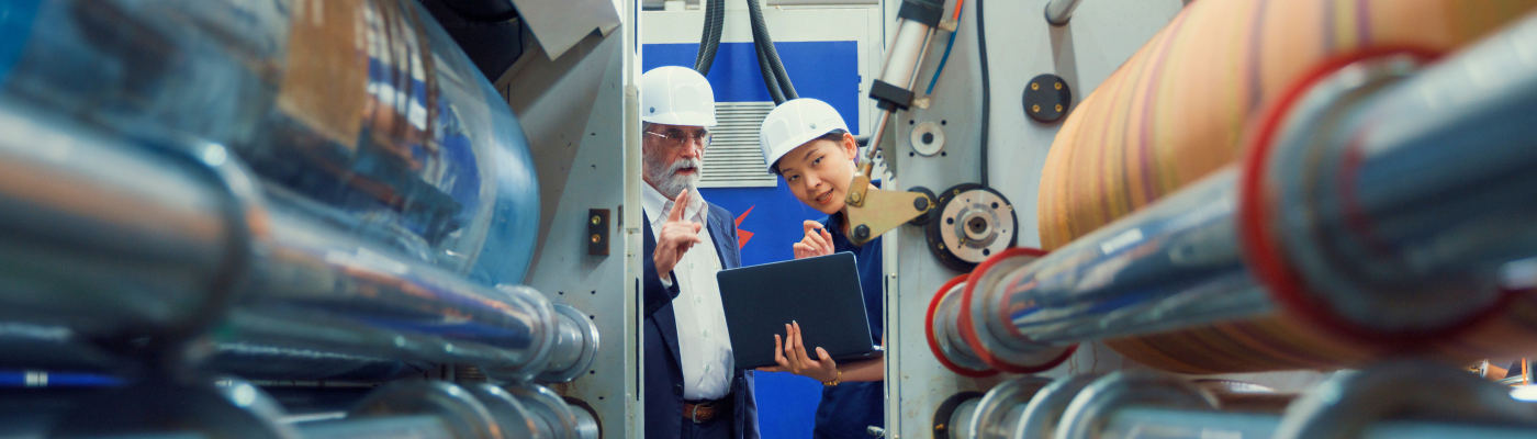 Professional male industrial engineers talk with factory worker while using laptop in manufacturing factory