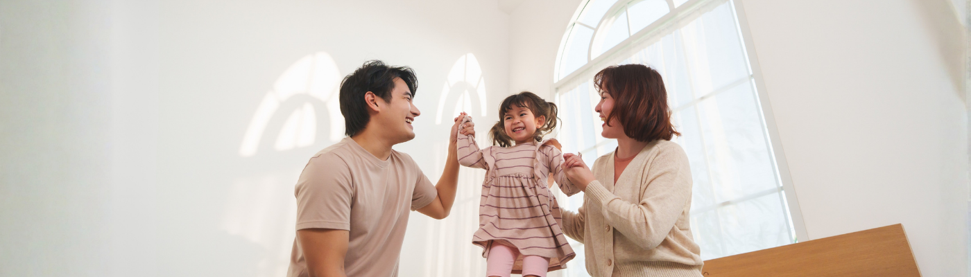 Asian parents playing with daughter on bed at home