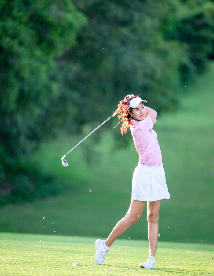 A woman is swinging a golf club