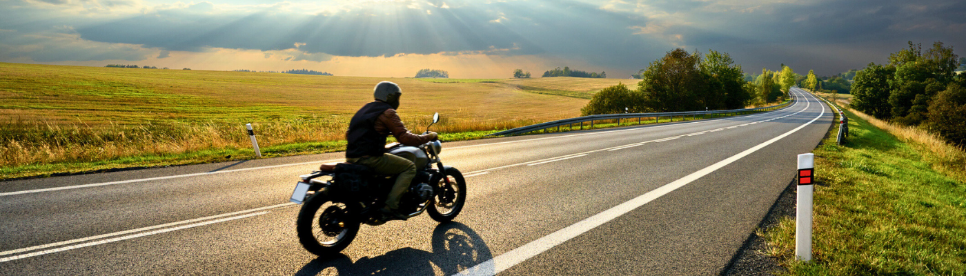 Motorcycle driving on the asphalt road in rural landscape
