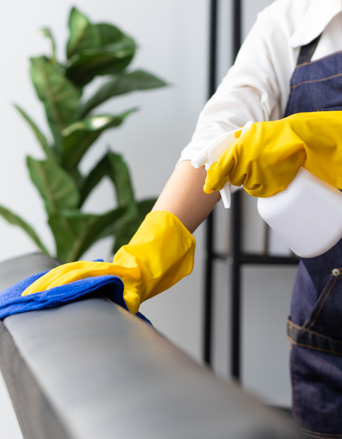 A house cleaner wearing an apron uses a cloth to clean