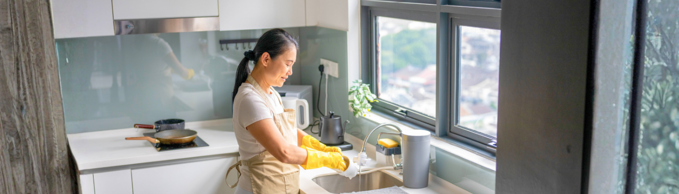 Asian housekeeper use towel to clean area in kitchen near sink