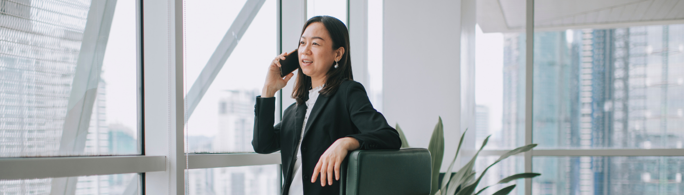 Asian chinese mid adult woman white collar worker working in her office room listening to her phone