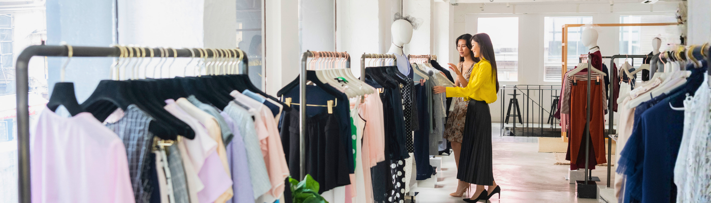 Chinese women choosing from clothes rail in shop