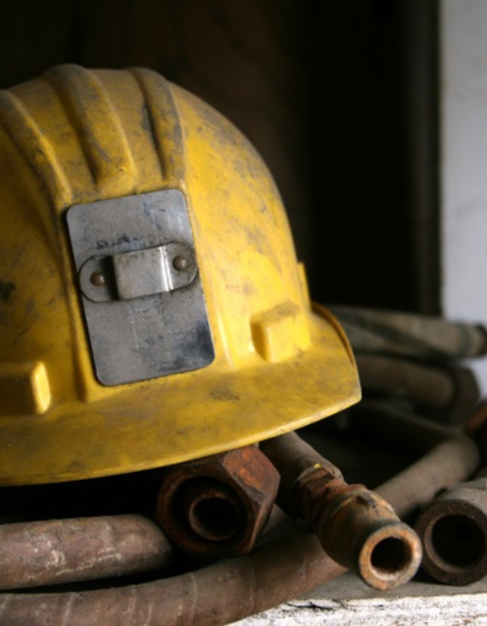 Close up of mining helmet on top of steel pipes