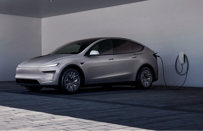 銀色 Tesla Model 3 停泊在有上蓋的停車棚下，並連接至壁掛式充電站。